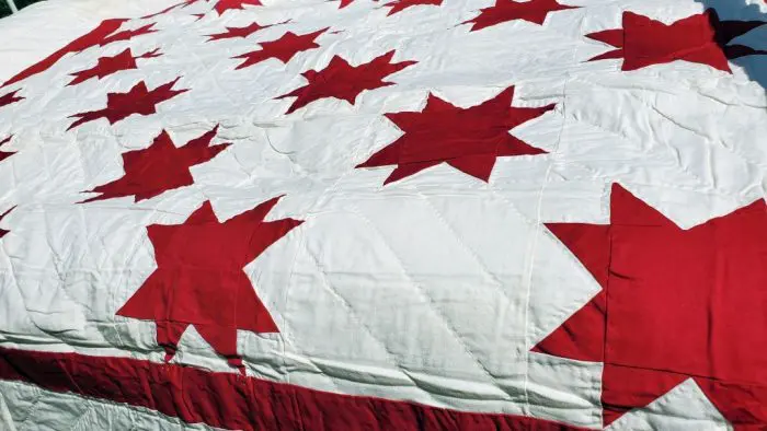 Burgundy RED Star Quilt Simple Red & White Cotton features red stars in a geometric design on a white background, ideal for bed coverage. The fabric is soft and slightly textured quilted.