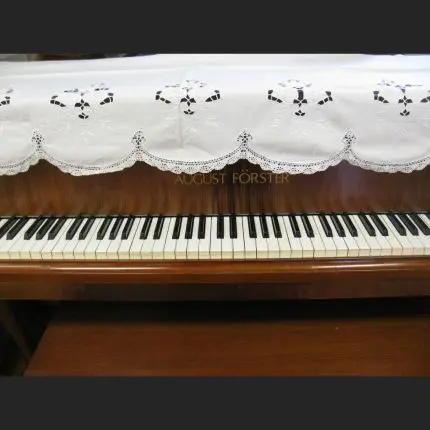 A close-up of a piano keyboard, with the Cluny Lace Piano Cover Scarf with Richelieu Embroidery (90"x30") partially covering the uptight pisno top.
