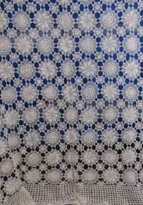 Ecru Snowflake Crochet BedCover featuring intricate circular patterns in Ecru, set against a blue backdrop, with its design showcasing repeated alternate motifs for a delicate, elegant texture.