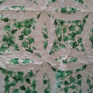 A quilt featuring a circular geometric design throughout with a pattern of green leaves and vines on a white background, known as the Irish Green & White Double Wedding Ring Handmade Quilt.