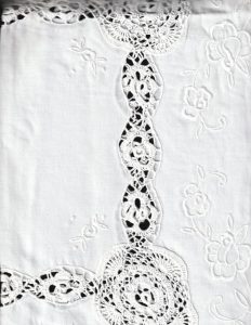 The Crochet Lace Roses 4 Corners Tea Tablecloth features delicate floral embroidery and intricate circular and oval lace designs in white or ecru, arranged in rows on a plain background for an elegant square table setting.