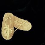 A pair of Crochet Lace & Ribbons Ivory Cotton Bedroom Slippers with satin lining, presented against a black background. The slippers are positioned with one slightly overlapping the other.