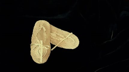 A pair of Crochet Lace & Ribbons Ivory Cotton Bedroom Slippers with satin lining, presented against a black background. The slippers are positioned with one slightly overlapping the other.