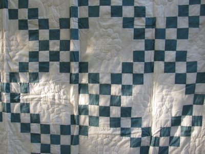 The Double Irish Chain Handmade Quilt in antique green showcases a vintage geometric checkerboard pattern in green and ivory squares, featuring intricate stitching with floral designs in the ivory sections for a textured appearance.