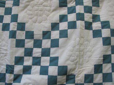 The Double Irish Chain Handmade Quilt - Antique Green features a grid pattern of Green and ivory squares, with intricately quilted floral designs in some ivory squares, adding texture and detail to its geometric pattern.