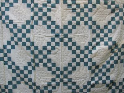The Double Irish Chain Handmade Quilt in antique green showcases an intricate geometric pattern with interlocking squares and rectangles, creating a lattice effect, complemented by exquisite stitching.