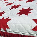 Burgundy RED Star Quilt Simple Red & White Cotton features red stars in a geometric design on a white background, ideal for bed coverage. The fabric is soft and slightly textured quilted.