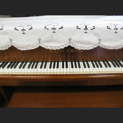 A close-up of a piano keyboard, with the Cluny Lace Piano Cover Scarf with Richelieu Embroidery (90"x30") partially covering the uptight pisno top.