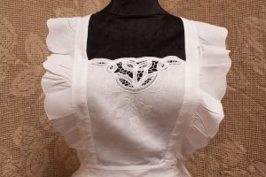 Close up view of White embroidered Tulips on the bib with wings on pinafore. Battenburg Lace shaped like tulips as decoration