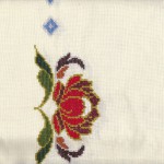 Needlework Peony on Pale Yellow cotton aida cloth close up view.