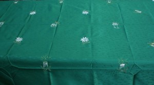 Christmas Celebration with embroidered X'Mas motifs on easy-cared green patterened polyester fabric. Gold trim is folded and well sewn and finished. Large size tablecloths available.